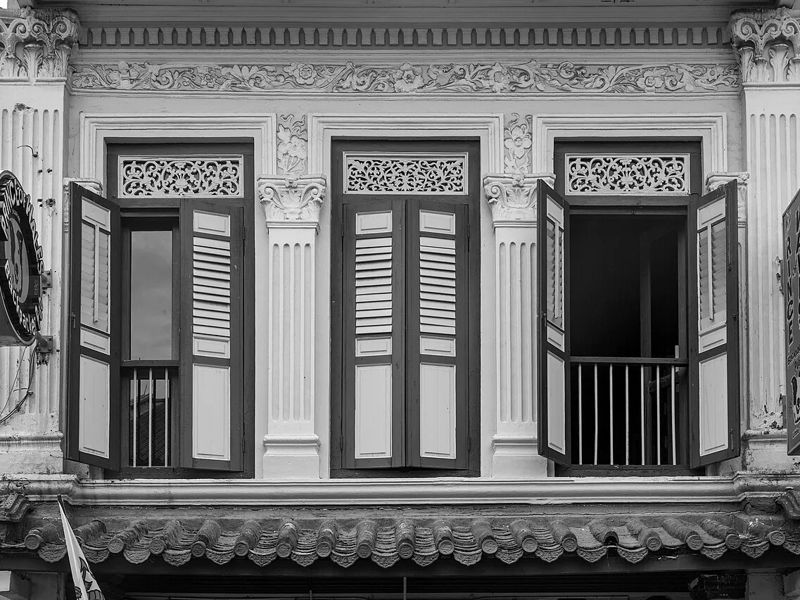 Jendela kayu dengan ornamen di fasad rumah toko tua